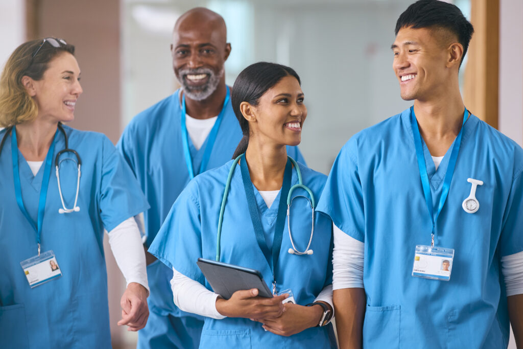 smiling multi cultural medical team wearing scrubs talking in modern hospital